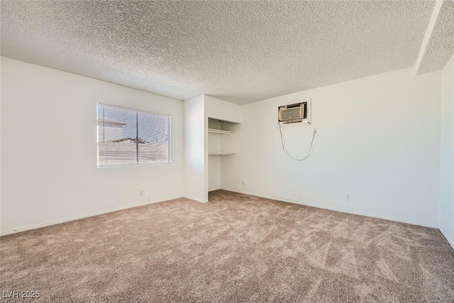 empty room featuring a textured ceiling, carpet floors, and a wall mounted air conditioner