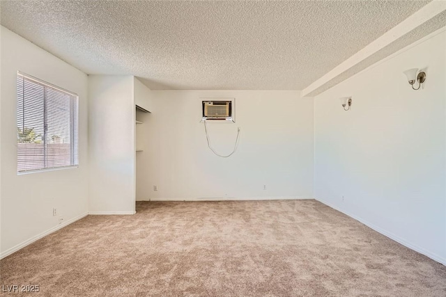 unfurnished room featuring carpet, an AC wall unit, and a textured ceiling