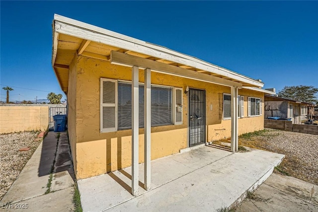 exterior space with a patio area, fence, and stucco siding