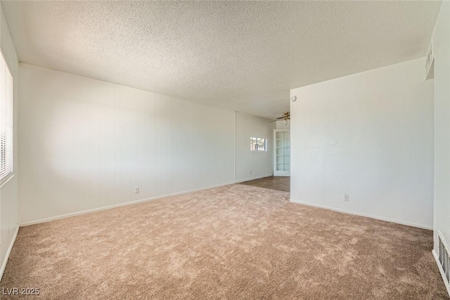 carpeted spare room with baseboards and a textured ceiling