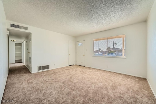 empty room with carpet, visible vents, and baseboards