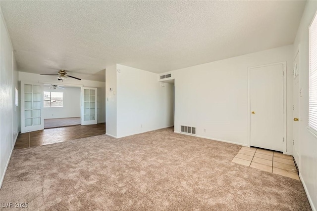 unfurnished room featuring a textured ceiling, carpet, and visible vents