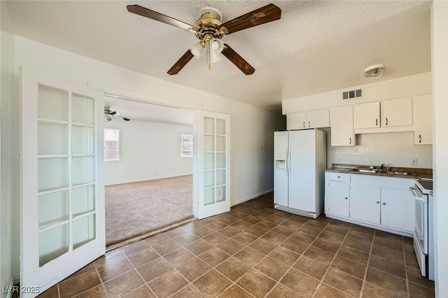 kitchen featuring white appliances, white cabinets, dark countertops, french doors, and a sink