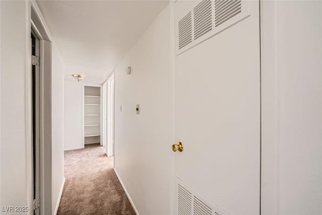 hallway with carpet, visible vents, and baseboards