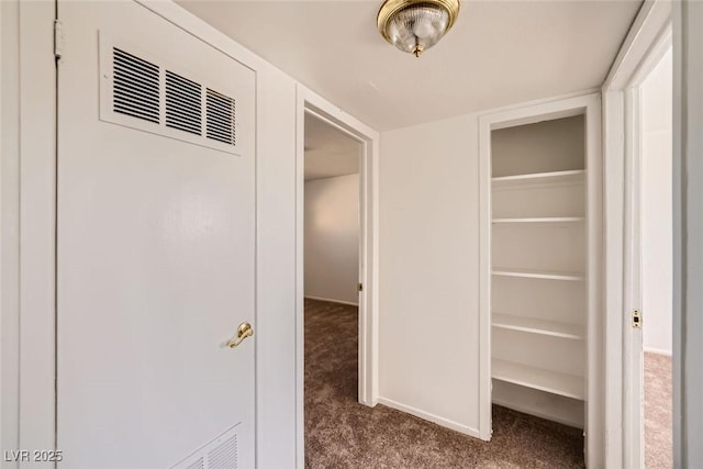 hall with carpet floors, baseboards, and visible vents