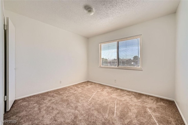 empty room featuring carpet flooring, a textured ceiling, and baseboards