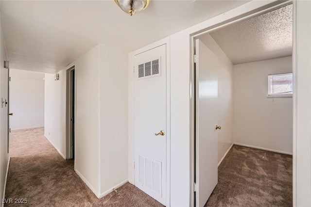 hallway with carpet, visible vents, a textured ceiling, and baseboards