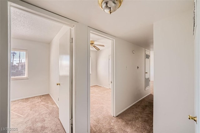 corridor with carpet, a textured ceiling, and baseboards