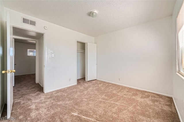 unfurnished bedroom with a textured ceiling, carpet flooring, visible vents, and baseboards