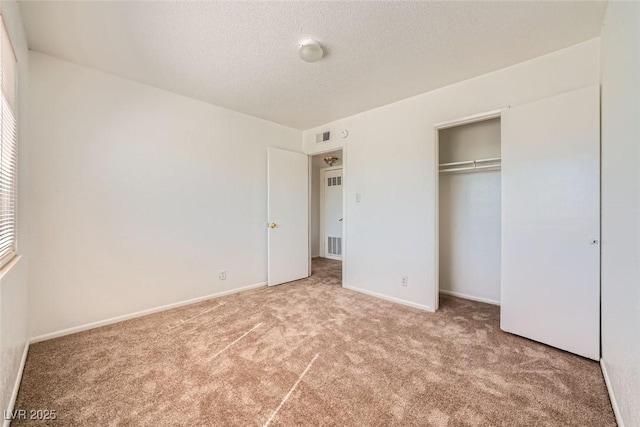 unfurnished bedroom with baseboards, visible vents, a textured ceiling, carpet flooring, and a closet