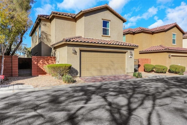 mediterranean / spanish-style house with decorative driveway, stucco siding, a gate, fence, and a garage