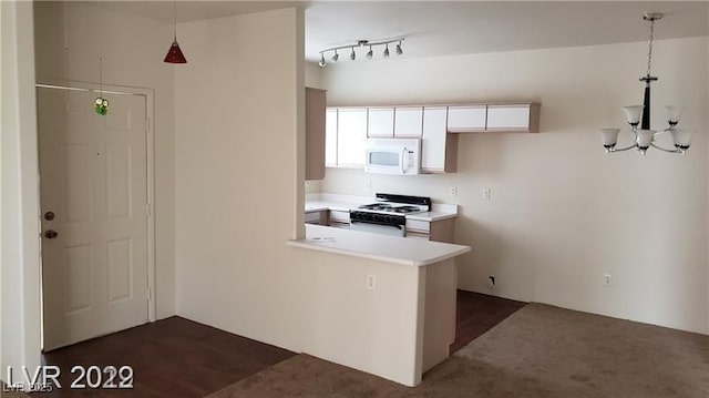 kitchen featuring white microwave, a peninsula, white cabinetry, light countertops, and gas range oven