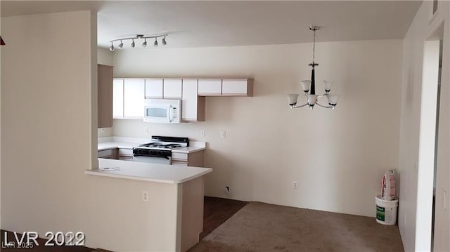 kitchen featuring white appliances, white cabinets, a peninsula, light countertops, and a chandelier