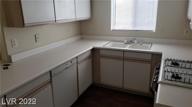 kitchen with gas stove, light countertops, white dishwasher, and a sink