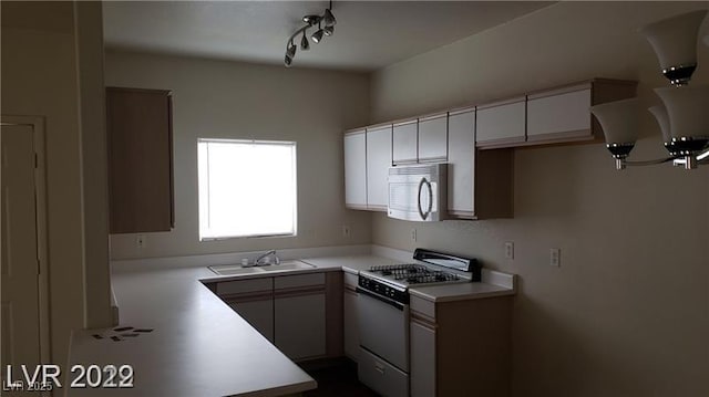 kitchen with white appliances, light countertops, a sink, and track lighting