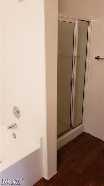 bathroom featuring a shower stall, a bathing tub, and wood finished floors