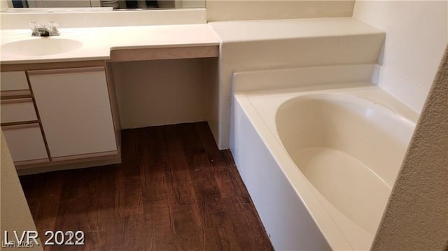 full bathroom featuring a bath, wood finished floors, and vanity