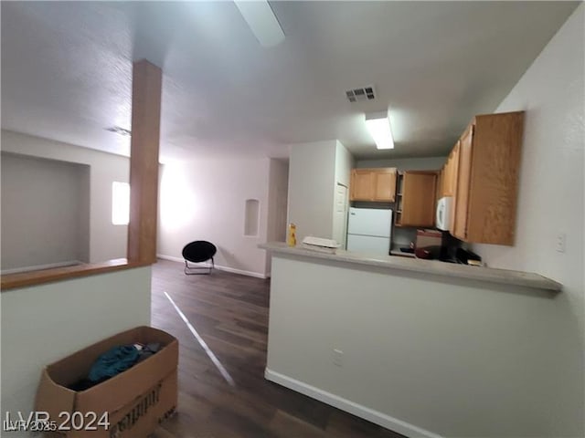 kitchen with white appliances, baseboards, visible vents, dark wood-type flooring, and a peninsula