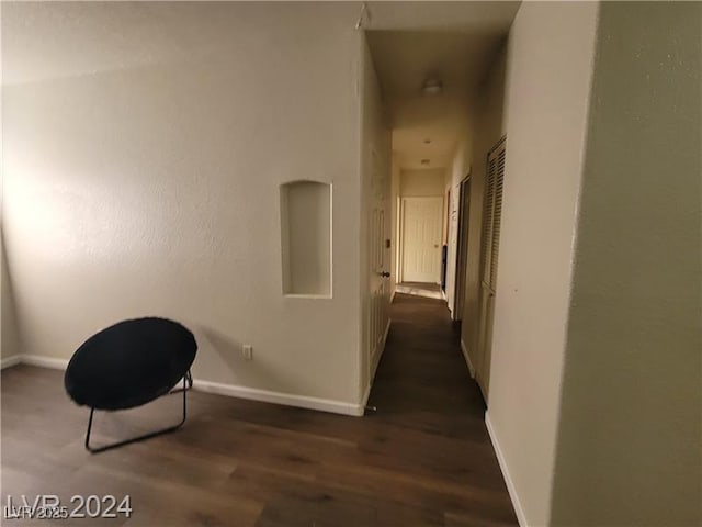 hallway featuring dark wood finished floors and baseboards