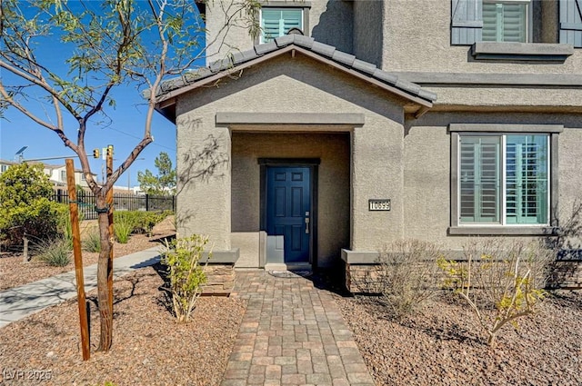 property entrance featuring fence and stucco siding