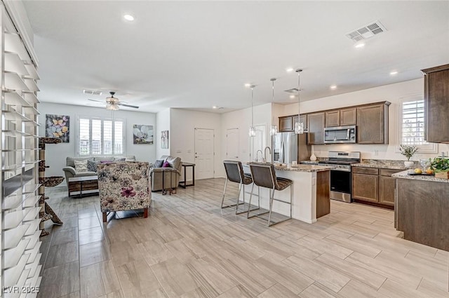 kitchen featuring stainless steel appliances, open floor plan, visible vents, and a breakfast bar area