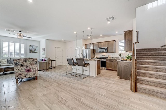 kitchen featuring appliances with stainless steel finishes, a breakfast bar, open floor plan, and visible vents