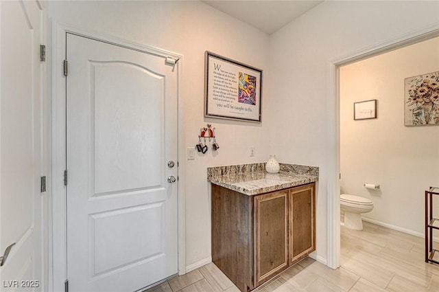 bathroom with toilet, baseboards, and wood finished floors