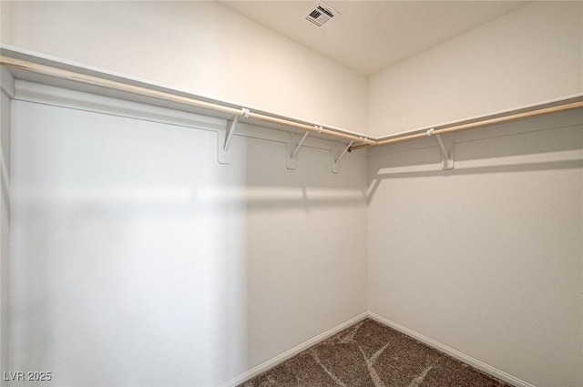 spacious closet featuring dark colored carpet and visible vents