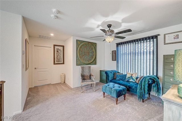 living area featuring a ceiling fan, baseboards, visible vents, and carpet flooring