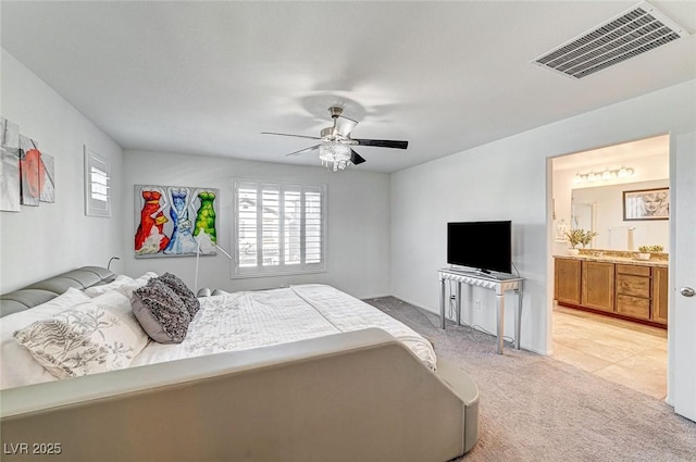 bedroom featuring light carpet, a ceiling fan, visible vents, and ensuite bathroom