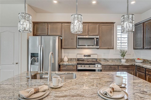 kitchen with light stone countertops, a notable chandelier, stainless steel appliances, and a sink