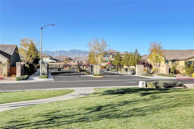 view of road featuring a residential view, a gate, sidewalks, and a gated entry