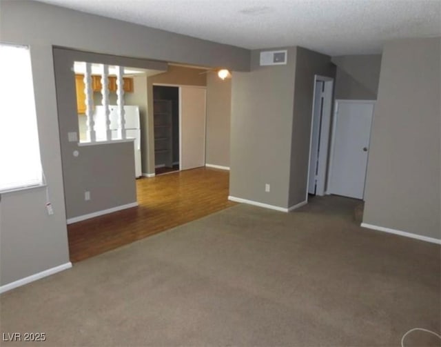 spare room with baseboards, visible vents, and carpet flooring