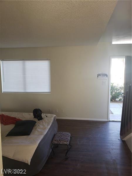 bedroom featuring access to outside, a textured ceiling, baseboards, and dark wood-type flooring