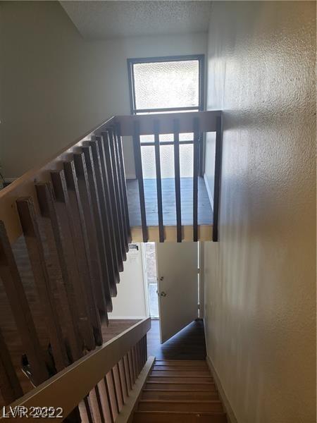 stairs featuring a textured ceiling and wood finished floors