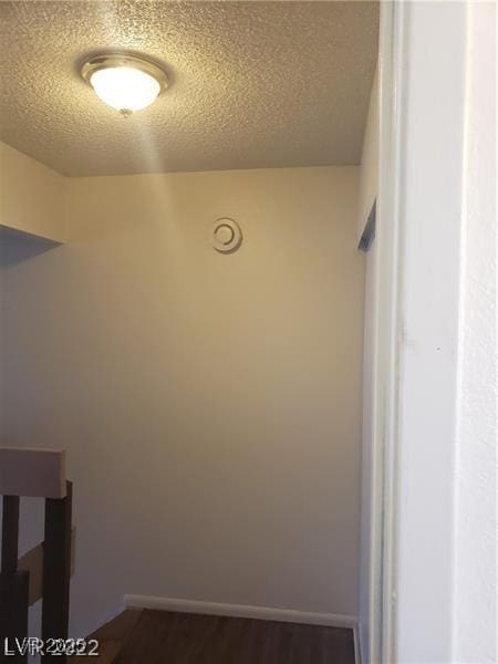 interior space with dark wood-style floors, a textured ceiling, and baseboards