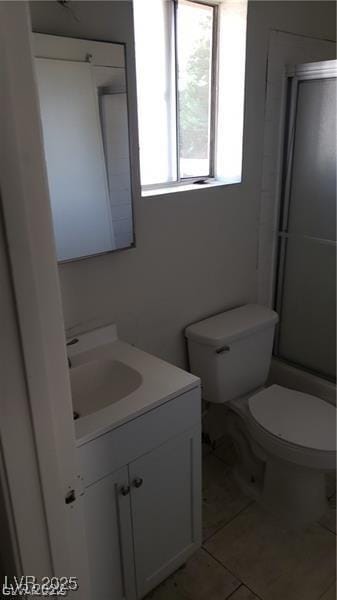 bathroom with toilet, tile patterned floors, vanity, and a shower with shower door