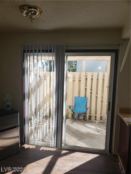 doorway to outside featuring a textured ceiling and wood finished floors