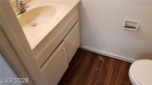 half bath featuring toilet, wood finished floors, and vanity