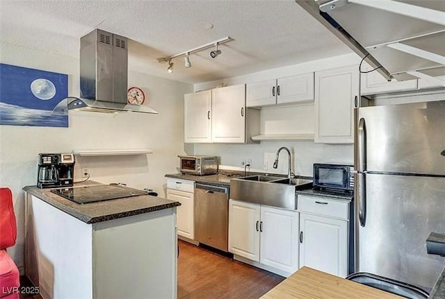 kitchen with black appliances, ventilation hood, dark countertops, and white cabinetry