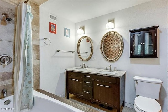 full bath featuring toilet, double vanity, visible vents, and a sink