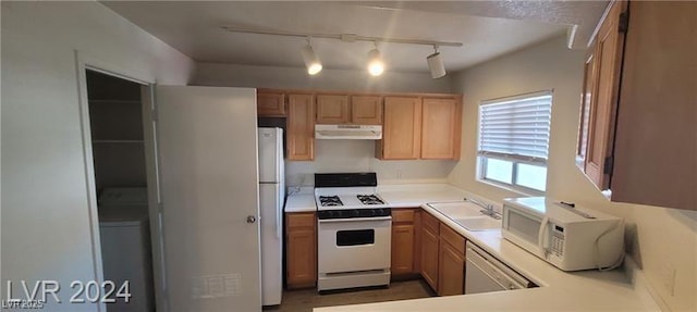 kitchen with white appliances, under cabinet range hood, light countertops, and a sink