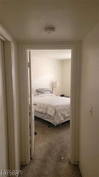 hallway with a textured ceiling and carpet flooring