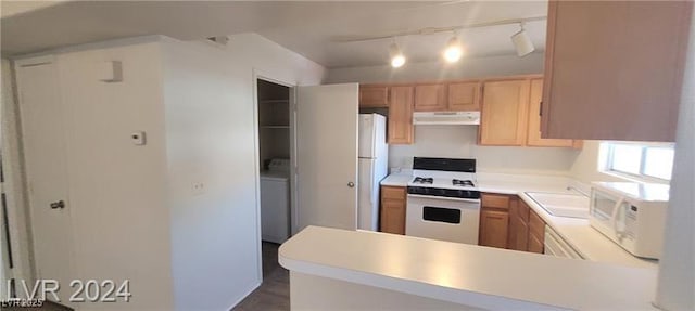 kitchen featuring washer / clothes dryer, light countertops, a sink, white appliances, and under cabinet range hood