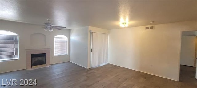 unfurnished living room with a ceiling fan, visible vents, a fireplace, and wood finished floors