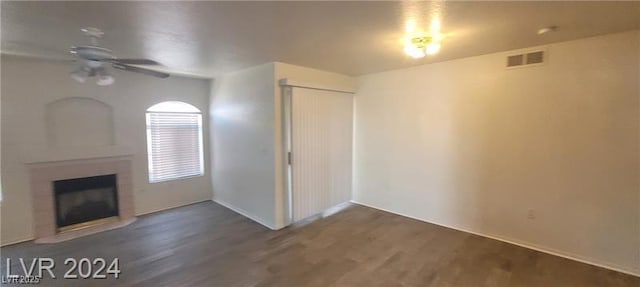 unfurnished living room featuring a ceiling fan, a fireplace, visible vents, and wood finished floors