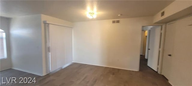 unfurnished bedroom with a closet, wood finished floors, and visible vents