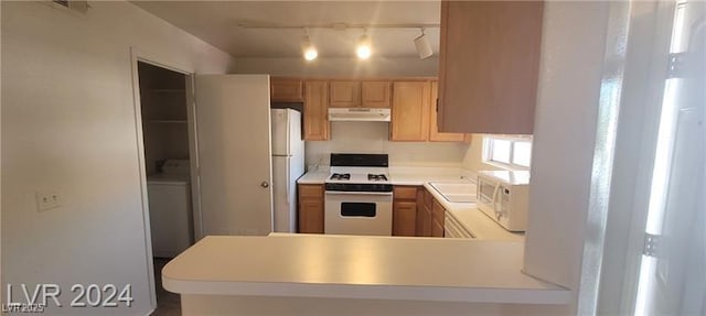 kitchen with light countertops, a sink, washer / dryer, white appliances, and under cabinet range hood