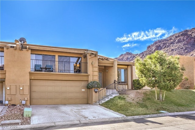 view of front facade with a garage, concrete driveway, a balcony, a mountain view, and stucco siding