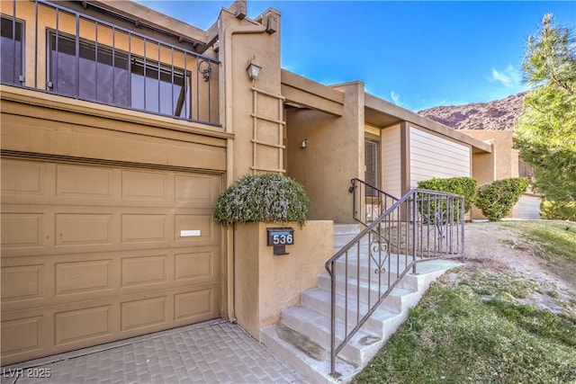 view of front of home featuring a garage, a mountain view, and stucco siding